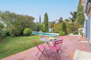 une terrasse avec des chaises roses et une table à côté de la piscine dans l'établissement Le Puy du Roy - Climatisé et piscine privée, à Aix-en-Provence