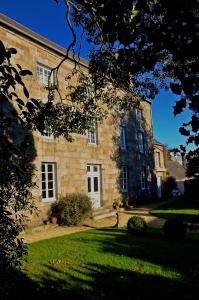 un antiguo edificio de piedra con un patio de césped delante de él en Maison de Benedicte, en Saint-Brieuc