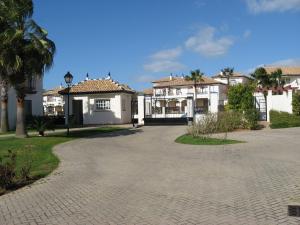 a row of white houses with palm trees and a driveway at Isla Canela Appartment in Isla Canela