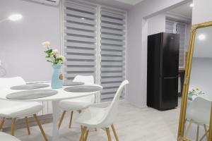 a dining room with white chairs and a table and a refrigerator at Apartament z Balkonem in Jastrzębie Zdrój