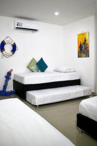 two beds in a room with white walls at Migaloo Hostal Rodadero in Puerto de Gaira