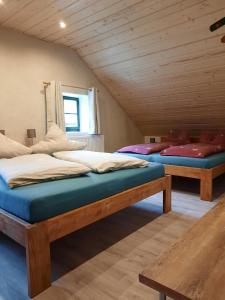 two beds in a room with wooden ceilings at Steinhaus / Kamenny Dum in Zdíkov