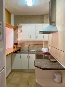 a kitchen with white cabinets and a sink at Apartamentos Ferrer in Es Figueral Beach