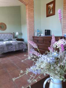 una sala de estar con una cama y un jarrón de flores en Els Canterers, en Miravet