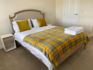 uma cama com um cobertor xadrez amarelo e azul em Westergate - 4 Bed Luxury Home with free parking em Milton Keynes