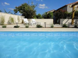 een zwembad met twee witte stoelen naast een huis bij Beautiful renovated farmhouse with private heated pool. in Saint-Pierre-dʼAmilly