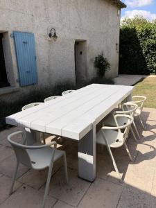 een witte tafel en stoelen met een witte tafel bij Beautiful renovated farmhouse with private heated pool. in Saint-Pierre-dʼAmilly