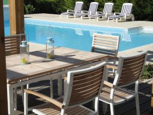 een houten tafel en stoelen naast een zwembad bij Beautiful renovated farmhouse with private heated pool. in Saint-Pierre-dʼAmilly