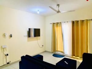 uma sala de estar com cortinas amarelas e uma televisão em Lux Suites Palm Terraces Apartments Nyali em Nyali