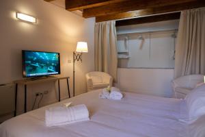 a bedroom with a large white bed with a flat screen tv at Le Maree Deluxe Apartment by Dimore Trinacria in Siracusa