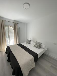 ein weißes Schlafzimmer mit einem großen Bett mit Kissen in der Unterkunft Apartamento Carihuela in Torremolinos