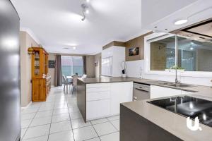 a large kitchen with white cabinets and a table at Blue Haven Retreat - Glenmore Park Pool Home in Glenmore Park