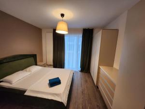 Un dormitorio con una cama con un libro azul. en Cloud9 Residence Great Apartments, en Bucarest