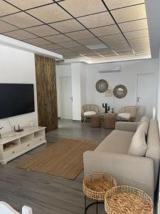 a living room with a couch and a flat screen tv at Casita coqueta en Agua Amarga in Agua Amarga
