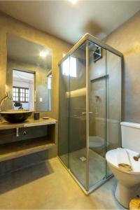 uma casa de banho com uma cabina de duche em vidro e um WC. em Charmoso Chalé Triplex - Centro da Pipa em Pipa