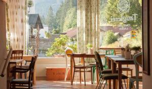 restauracja ze stołami i krzesłami oraz dużym oknem w obiekcie Tauglerei Appartement Bernstein in den Zauberbergen w mieście Sankt Koloman