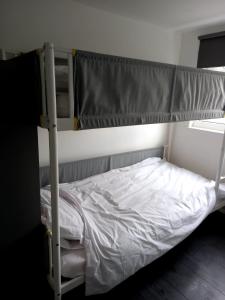 a bedroom with a bunk bed with white sheets at Byron View House in Luton