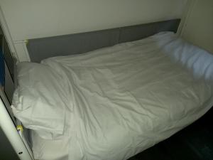Una cama con sábanas blancas en una habitación pequeña. en Byron View House en Luton