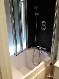 a bath tub with a shower in a bathroom at Manor Green Cottage in Windsor +2 photos