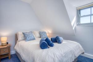 Un dormitorio con una cama con almohadas azules y una ventana en Ocean Cabins No 13 At The Square - Saundersfoot en Saundersfoot
