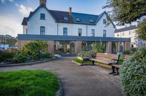 una casa con dos bancos delante en Ocean Cabins No 10 At The Square - Saundersfoot en Saundersfoot