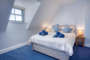 a bedroom with a bed with blue pillows and a window at Ocean Cabins No 14 At The Square - Saundersfoot in Saundersfoot