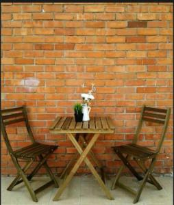 una mesa y dos sillas junto a una pared de ladrillo en Cozy-SJ-Family Holidays-Work-BBQ-Tea ceremony-Engagement en Subang Jaya