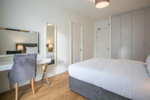1 dormitorio con cama, escritorio y espejo en Grand Canal Square Apartments, en Dublín