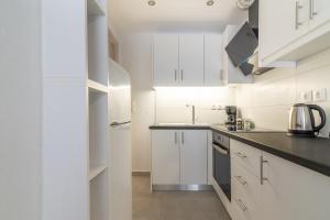 a kitchen with white cabinets and black counter tops at Stylish & relax flat for friends & couples in Heraklio Town +19 photos