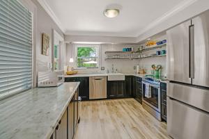 a kitchen with black cabinets and stainless steel appliances at Coastal Soul House in the heart of Naples in Naples