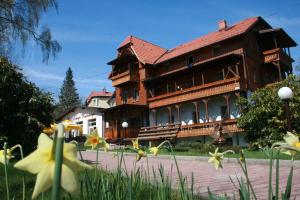 ein großes Holzgebäude mit gelben Blumen davor in der Unterkunft Hotel Narcyz in Świeradów-Zdrój
