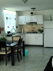 Caracoles Breeze Apartments في Islote: مطبخ مع طاولة وثلاجة بيضاء