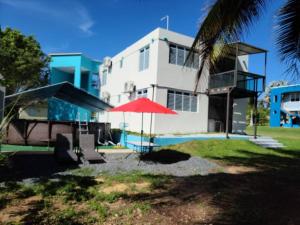 a white building with a red umbrella and a pool at Caracoles Breeze Apartments in Islote