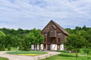 a large wooden house in the middle of a field at Klumpes Malunas in Vosbutai
