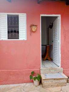 une maison rose avec une porte et une fenêtre dans l'établissement Pousada Acalanto, à Pirenópolis