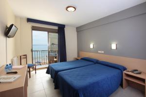 a hotel room with a blue bed and a balcony at Hotel Bilbaino in Benidorm