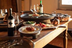 Campagnatico的住宿－Locanda Fontelupa，餐桌,带食物盘和一瓶葡萄酒