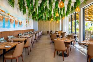 a restaurant with wooden tables and chairs and plants on the ceilings at AP Cabanas Beach & Nature - Adults Friendly in Cabanas de Tavira