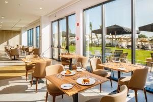 a restaurant with tables and chairs and large windows at AP Cabanas Beach & Nature - Adults Friendly in Cabanas de Tavira
