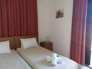 two twin beds in a room with red curtains at Papas Studios in Skala Marion