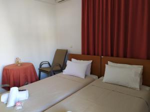 two beds in a room with a red curtain at Papas Studios in Skala Marion