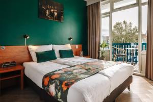 a bedroom with a large bed with a green wall at Hotel Keur in Zandvoort