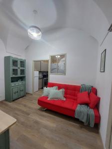ein Wohnzimmer mit einem roten Sofa und einer Küche in der Unterkunft I Tre Merli in Dolceacqua