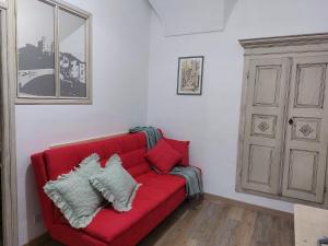 ein rotes Sofa mit Kissen im Wohnzimmer in der Unterkunft I Tre Merli in Dolceacqua