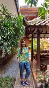 a woman is standing in front of a building at Ndalem Suryo Saptono Guest House in Yogyakarta