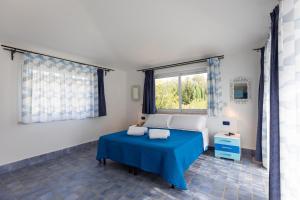 um quarto com uma cama azul e uma janela em Villa Kore, Capo Vaticano em Capo Vaticano