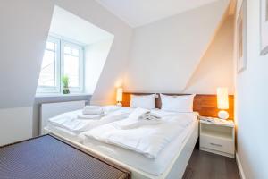 - une chambre blanche avec un grand lit et des draps blancs dans l'établissement Haus Nordmarkgarten Whg 7, à Westerland