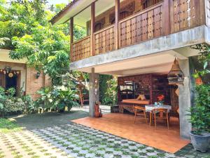 a house with a balcony with a table and a bed at Ndalem Suryo Saptono Guest House in Yogyakarta