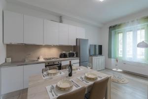 une cuisine blanche avec une table et des chaises et une cuisine avec des placards blancs dans l'établissement SANTACROCE suite-Hosted by Sweetstay, à Florence