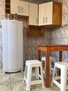 uma cozinha com um frigorífico, 2 bancos e uma mesa em excelente apartamento completo em Pelotas